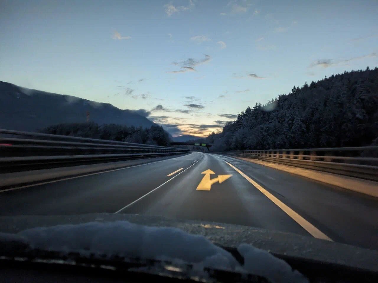 Blick aus dem Auto auf eine winterliche Straße am frühen Morgen.